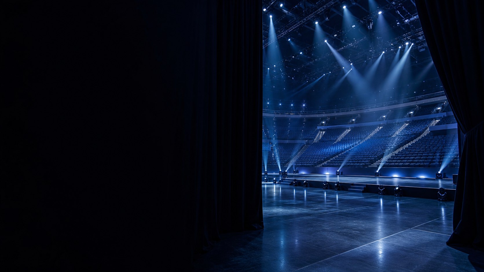 Empty arena viewed from backstage beneath blue production lights