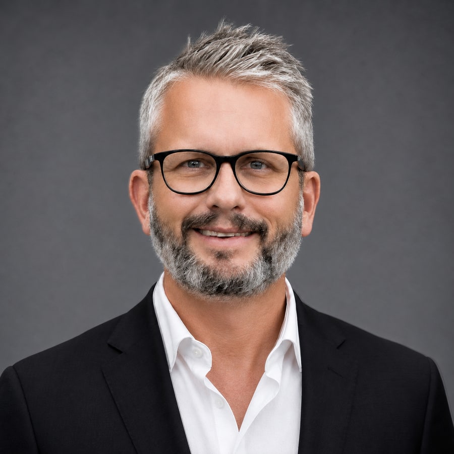 Portrait of Jeff Kirk in a black suit against a charcoal background