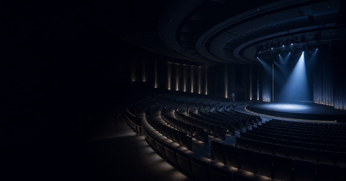An empty large-scale event venue shaped by curved seating and focused blue stage lighting