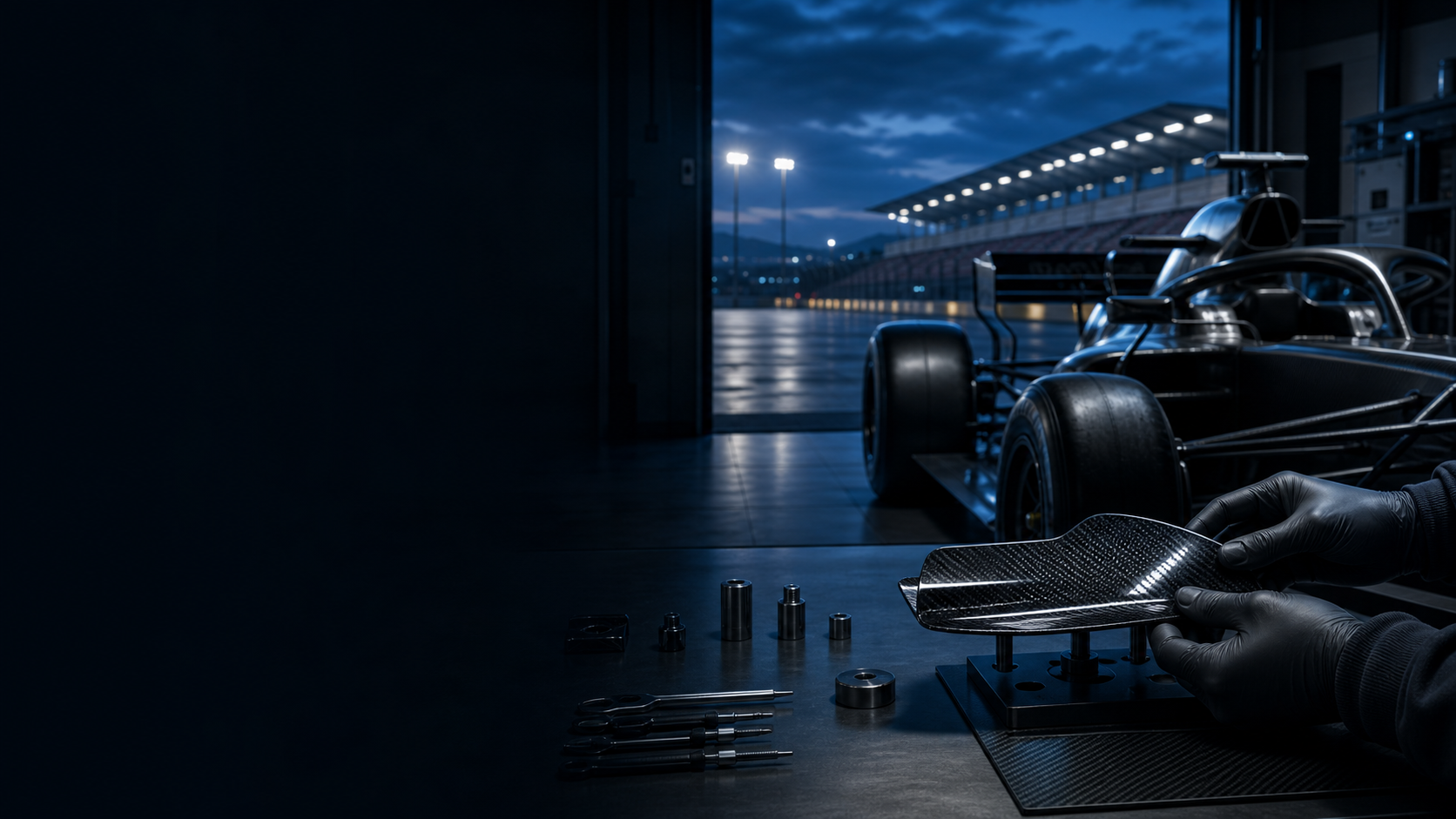 An unbranded Formula-style race car and a technician aligning a carbon-fiber component inside a precise pit garage at blue hour